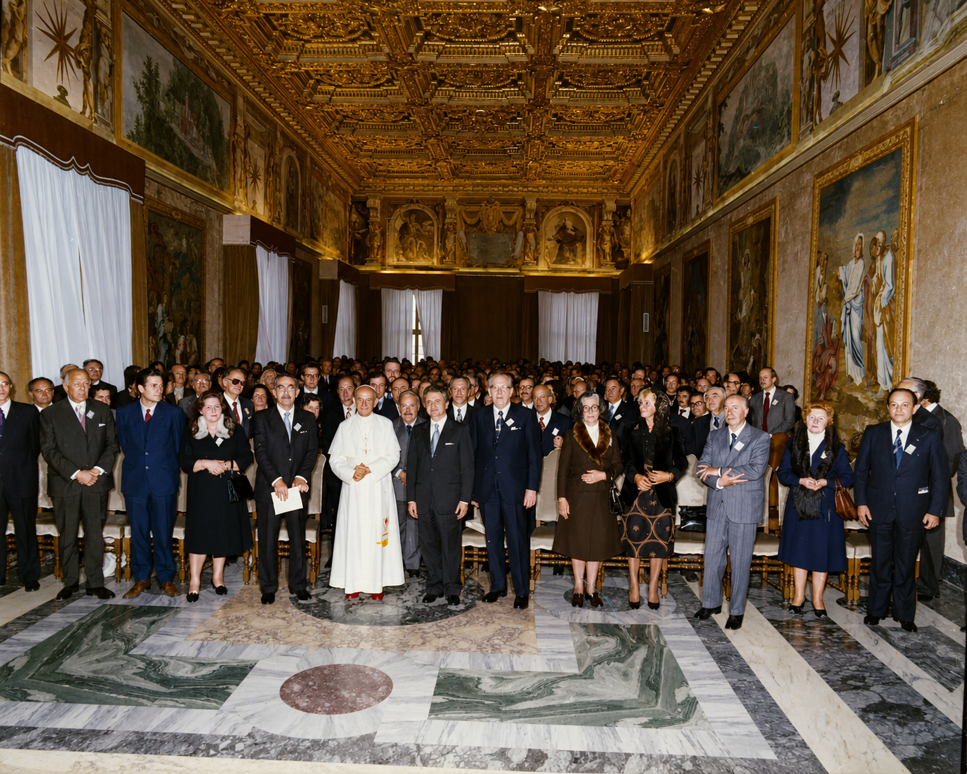 Vittorino Colombo partecipa a una cerimonia istituzionale in una prestigiosa sala di rappresentanza insieme a numerose autorità civili, religiose e politiche.